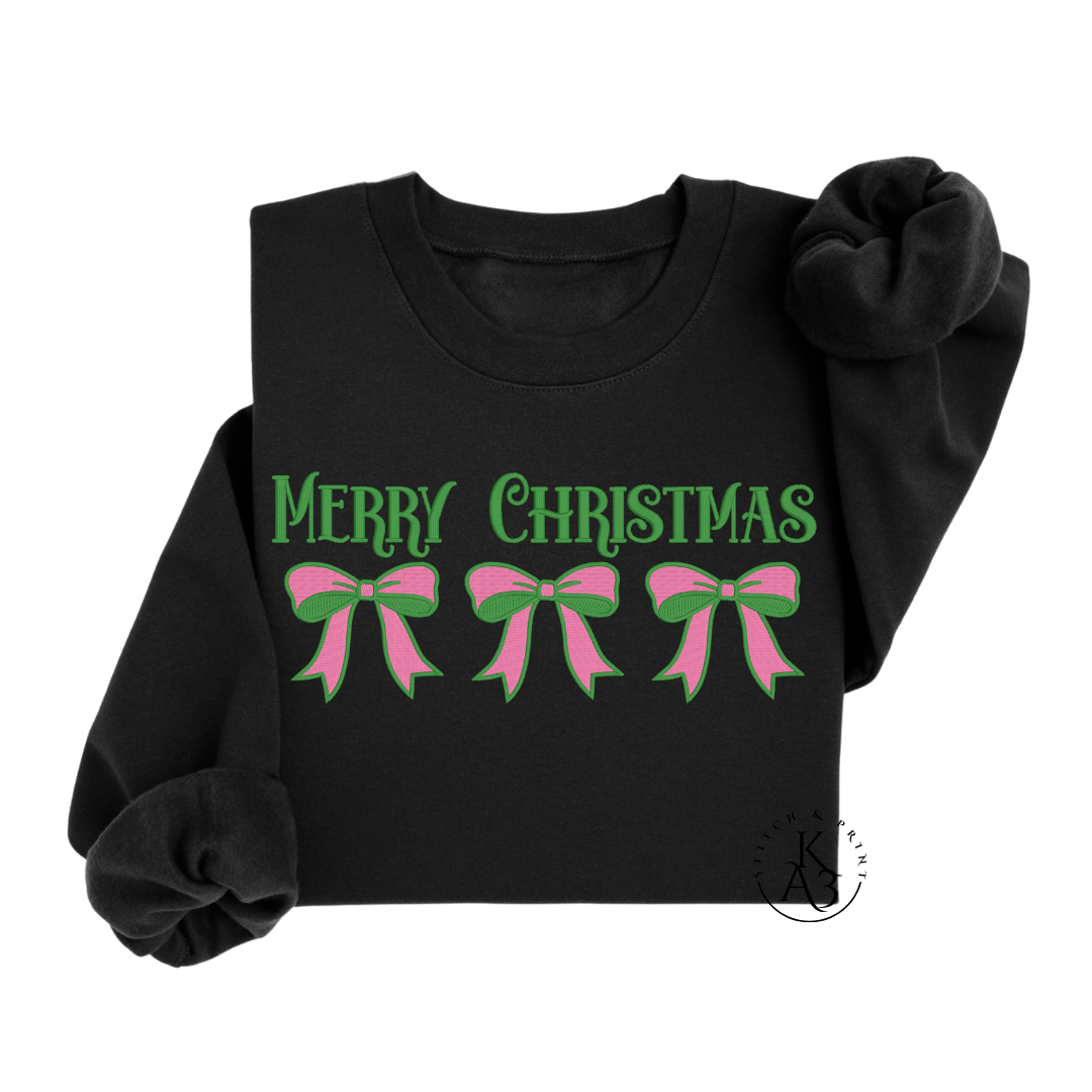 Black sweatshirt with embroidered 'Merry Christmas' and pink and green bow designs on a white background
