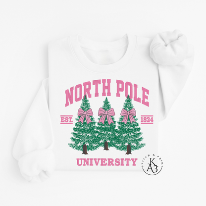 White Sweatshirt with embroidered green trees, pink bows, and 'North Pole University' text on a white background
