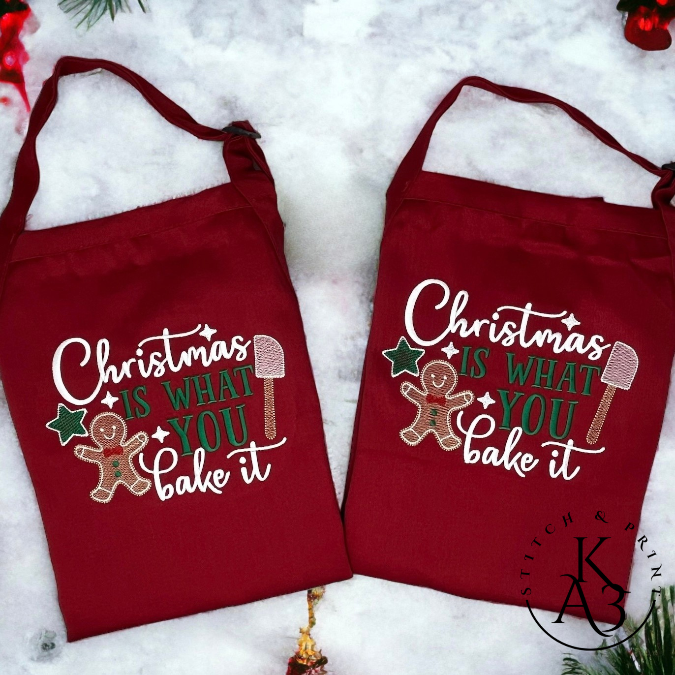 Two red aprons with Christmas-themed designs on a snowy background.