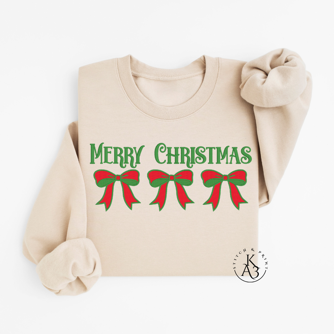 Beige sweatshirt with an embroidered 'Merry Christmas' text and red and green bows on a white background