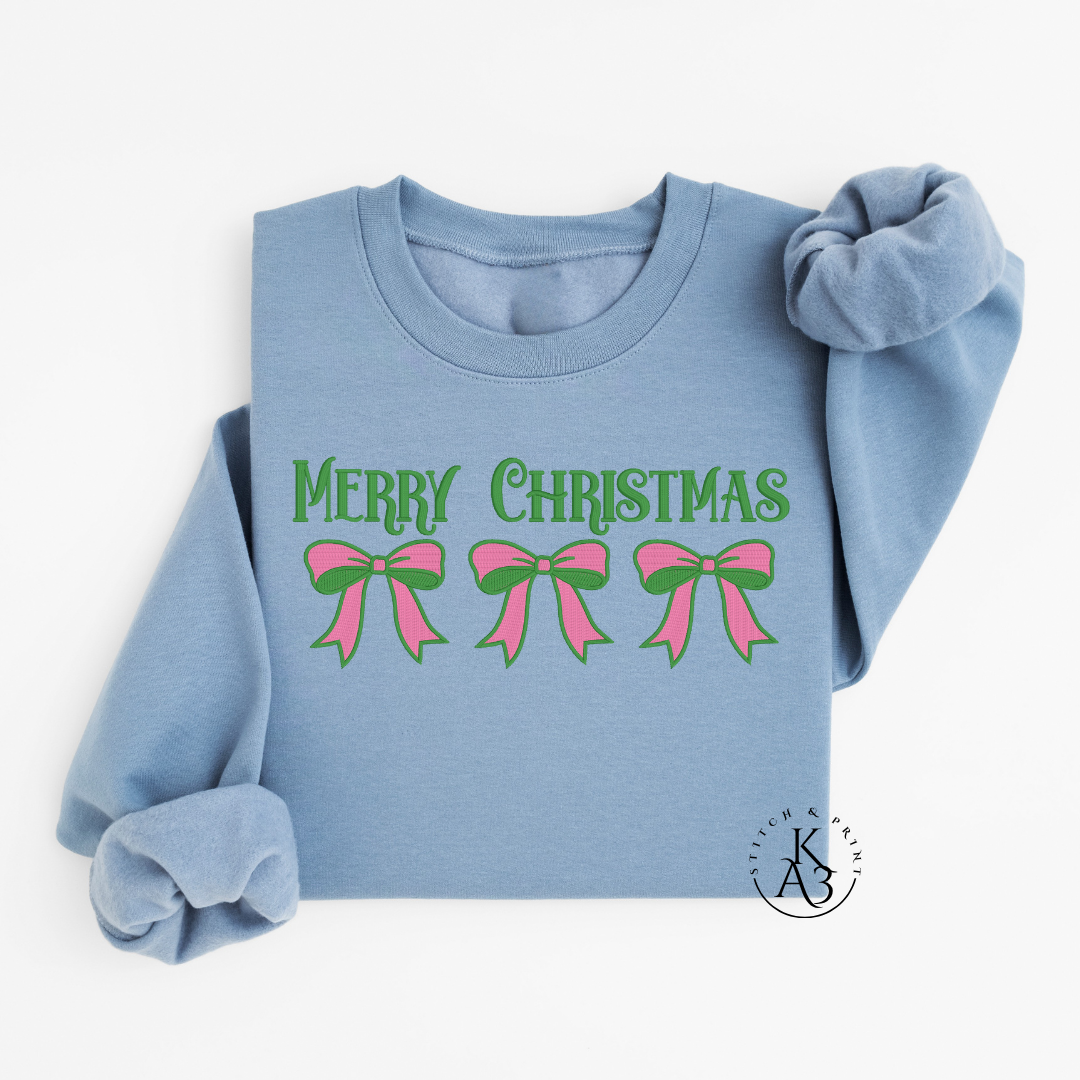 Light blue sweatshirt with embroidered 'Merry Christmas' and pink and green bows on a white background